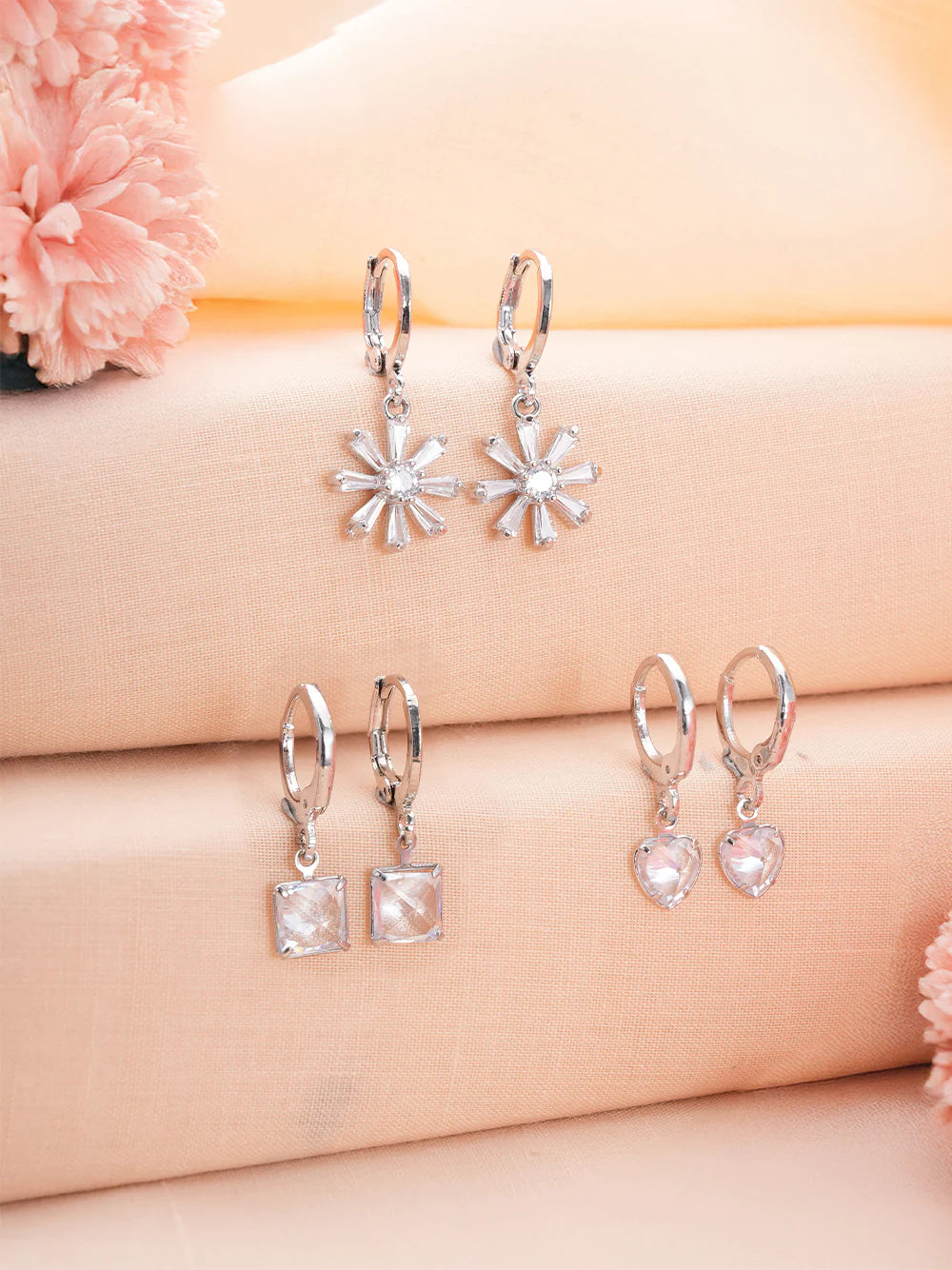 Three pairs of earrings in Zelci 's Floral Sparkle Trio have been presented on a decorative background