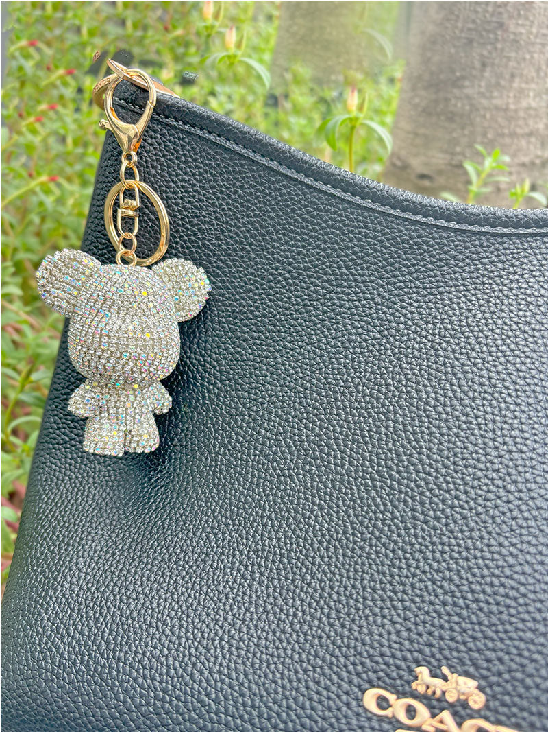 GlitzBear Keychain of Zelci is showcased hanging on the COACH bag