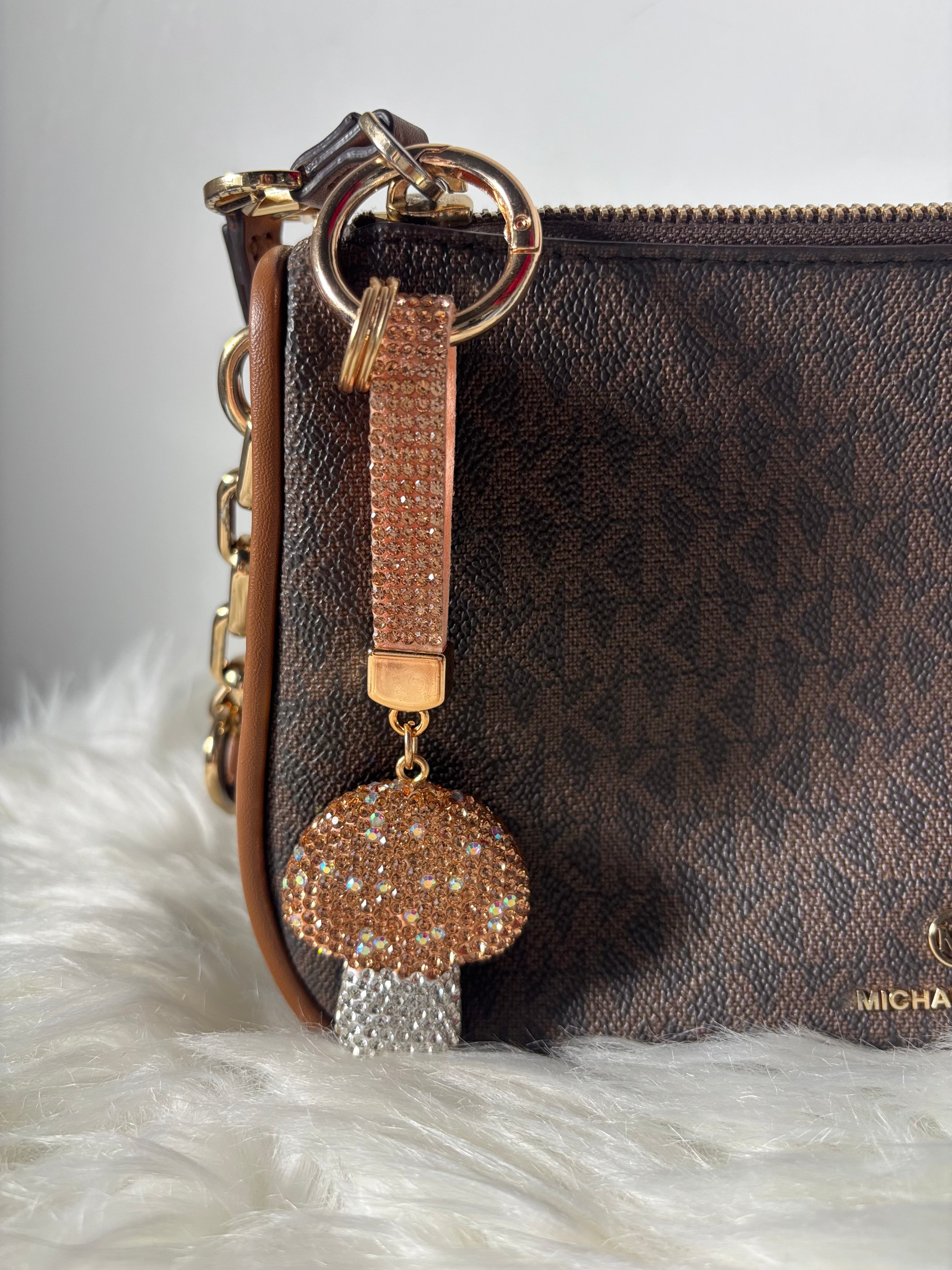 Brown handbag with a decorative keychain featuring a mushroom charm on a white fur surface.